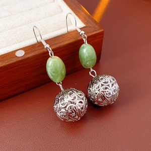 Detail of hollow silver metal sphere and green resin oval beads on vintage style ear hooks
