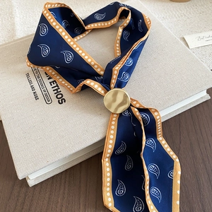 Detail of navy blue paisley silk scarf with gold wave-textured metal ring on vintage book