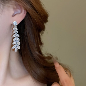 Silver drop earrings with sparkling wheat-shaped zircons shown on a model neck