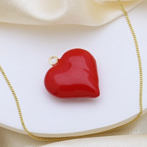 Elegante goldene Halskette mit glänzendem rotem Herzanhänger auf weißem Sockel