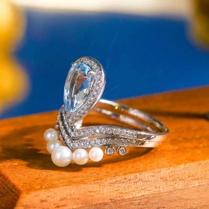 Detail of pear-cut aquamarine ring paired with a V-shaped white pearl nesting band