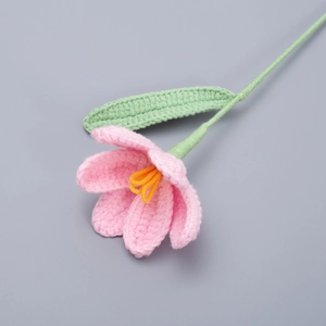 Close-up of handmade crochet tulip with pink yarn petals and green stem details