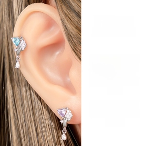 Detail of heart-shaped zircon earrings with blue and purple stones and teardrop charms