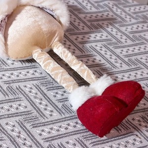 Detail of plush Christmas doll legs with red felt boots and gold velvet fabric texture