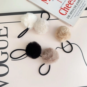 Detailed view of five plush hair ties in earth tones with elastic bands on a magazine