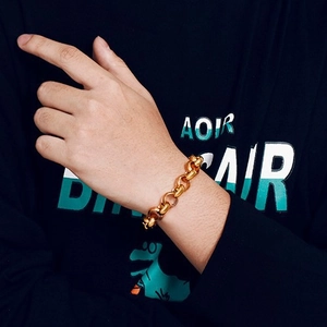 Chunky gold stainless steel chain bracelet for men and women on a person's wrist