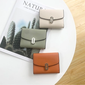 Three multi-color litchi grain leather mini wallets with metal buckles on a magazine