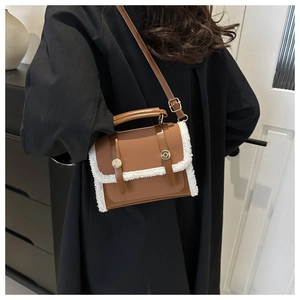 Brown leather crossbody bag with white fleece trim worn by model over black coat