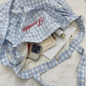 Detail of blue gingham tote bag showing spacious interior with books and magnetic closure