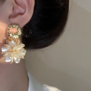 Elegant gold-plated flower earrings with shell-like petals on model for high-end fashion