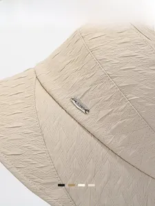 Detail of light beige sun hat showing geometric texture and silver metal tag
