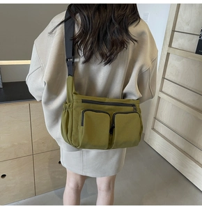 Detail of army green canvas crossbody bag featuring multi-pocket utility design and wide strap