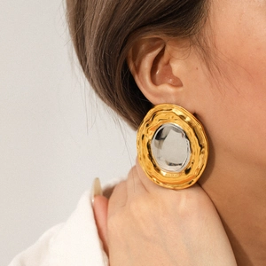 Close-up of oversized gold and silver contrast geometric hoop earrings on a model