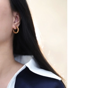 Close-up of model wearing caramel enamel hoops and 18K gold-plated stainless steel earrings