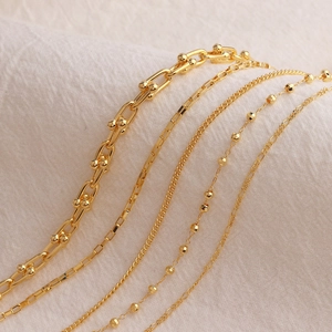 Minimalist gold plated copper necklaces featuring diverse chain links on textured fabric