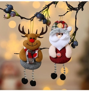 Detail of Santa and Reindeer fabric ornaments hanging on branches with warm bokeh lights