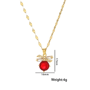 Detail view of a 17mm gold necklace with red gemstone and sparkling bow pendant