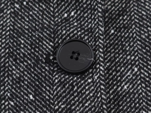 Macro detail of black and white herringbone fabric with a classic four-hole button