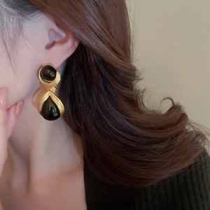 Close-up of retro dark style acrylic drop earrings with gold metal and black beads