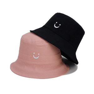 Detailed view of smiley face embroidery on black and pink cotton bucket hats