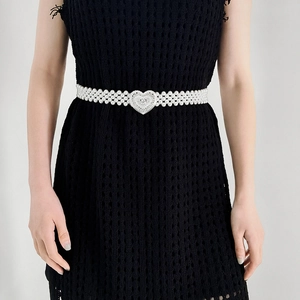 Detail view of multi-strand pearl waist belt with silver heart buckle on a black dress