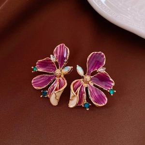 Detail of purple enamel flower earrings with gold edges and sparkling rhinestones