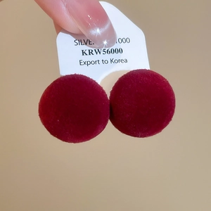 Detailed macro view of red velvet spherical earrings with flocking texture on display card