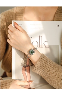 Close-up of vintage square watch with green dial and silver chain strap on wrist