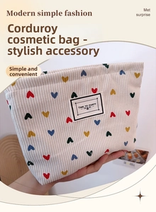 Detailed close-up of corduroy makeup bag with colorful heart embroidery and woven label