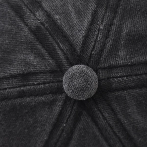 Gros plan sur le bouton supérieur et les coutures radiales de cette casquette en coton