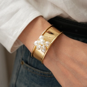 Detailed view of a gold cuff bracelet featuring a cluster of elegant white pearls