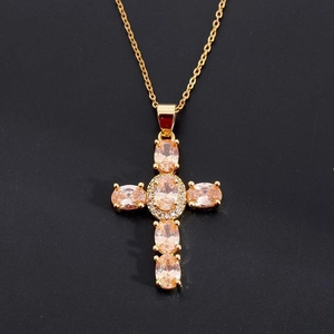 Macro shot of gold cross pendant necklace featuring champagne stones and zircon accents