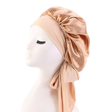 Detail of champagne satin sleep cap featuring long adjustable ribbons on a white mannequin