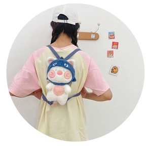 Rear view of a plush white cat backpack wearing a blue shark hat with thin straps