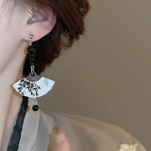 Close-up of fan-shaped drop earrings with bamboo ink painting on a model's ear