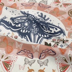 Close-up of woven fabric texture featuring a moth, stars, and moon on a bohemian tapestry