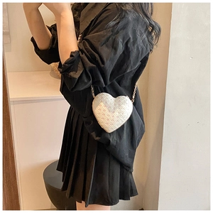 On-body view of a white heart-shaped sequin mini bag with elegant gold chain strap