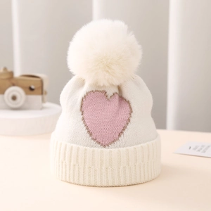 Detail of baby knitted hat with pink heart jacquard and white faux fur pompom
