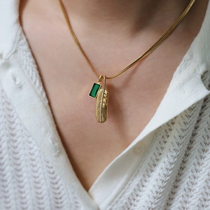 Vintage gold plated necklace featuring green gemstone and detailed feather pendants