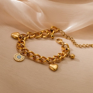 Gold-plated evil eye bracelet with heart charms on silk background