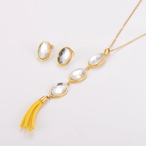 Detail of gold necklace and earrings set featuring white oval stones and yellow tassels