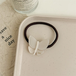 Detail view of a cream butterfly hair tie with France Handmade text on ceramic tray