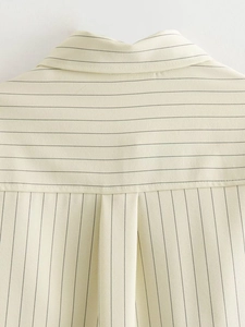 Close-up of the striped beige shirt collar and shoulder detail showing fine fabric texture