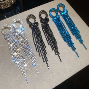 Close-up of sparkling geometric round tassel earrings in silver, black, and blue finishes