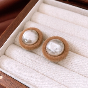 Close-up of vintage brown velvet round stud earrings with pearl inlay in a jewelry box