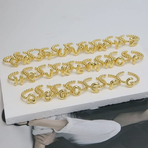 Detailed set of 18K gold alphabet rings with beaded texture on white platform