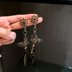 Detailed close-up of long tassel earrings with black crystals and golden butterfly charms
