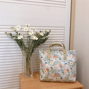 Floral tote bag with daisy patterns, brown faux leather handles and rivet details