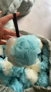 Close-up of a soft dual-tone blue and white loofah sponge with mesh texture and hanging cord