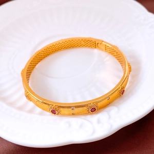 Vue macro du bracelet vintage plaqué or 24K avec gemmes rouges et motif en nid d'abeille